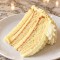 Representative slice of limoncello cake with lemon cream and whipped topping