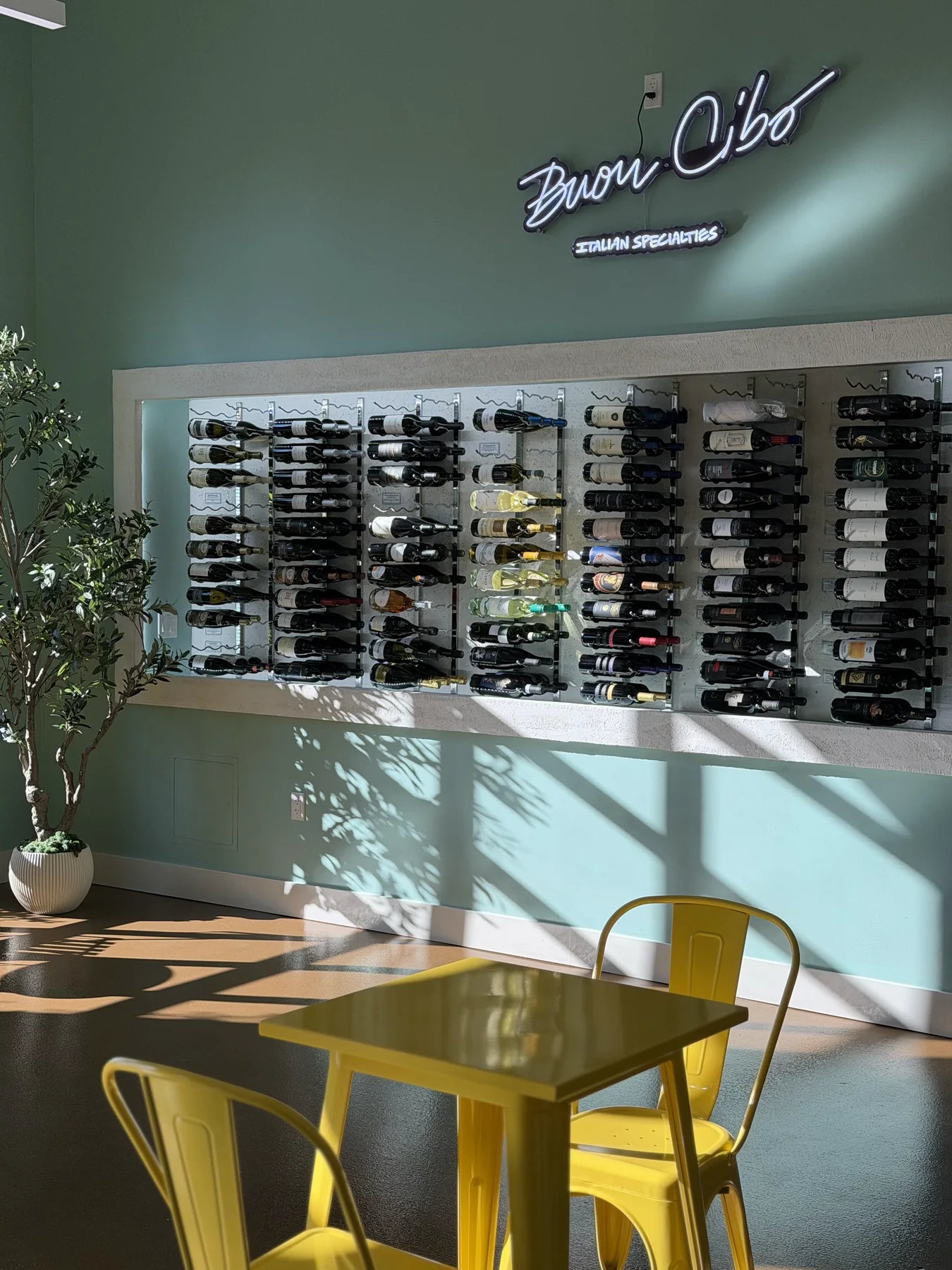 The Buon Cibo wine wall, racked bottles under the neon wordmark